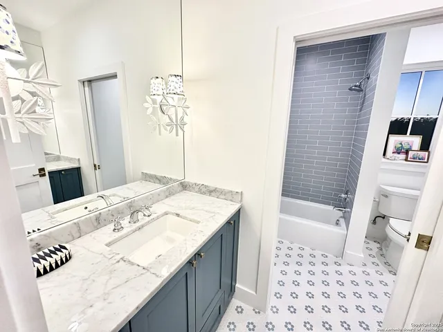 a bathroom with a granite countertop sink a mirror a bathtub and shower