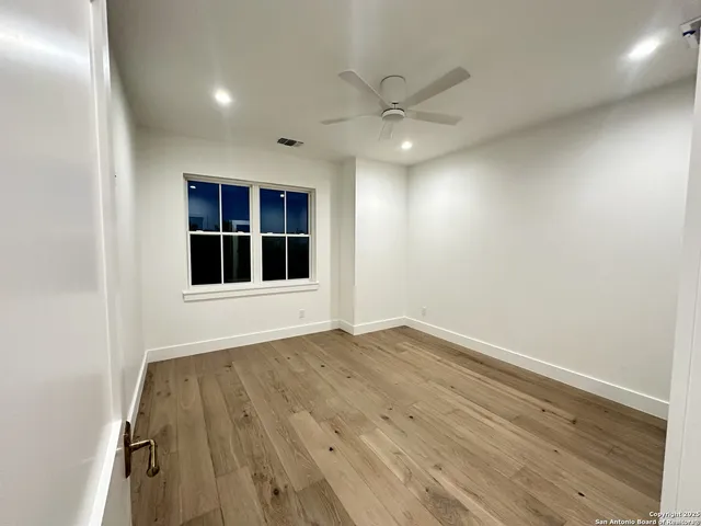 an empty room with wooden floor cabinet and windows