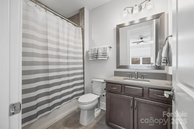 a bathroom with a sink a toilet a mirror and shower curtain