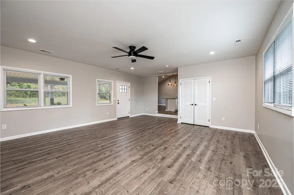 a view of an empty room with a window and wooden floor