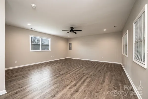 an empty room with wooden floor and windows