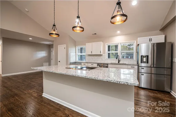 a kitchen with stainless steel appliances granite countertop a sink a refrigerator and a stove