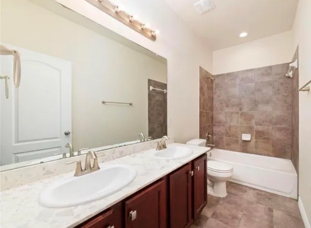 a bathroom with a granite countertop bathtub sink double vanity and mirror