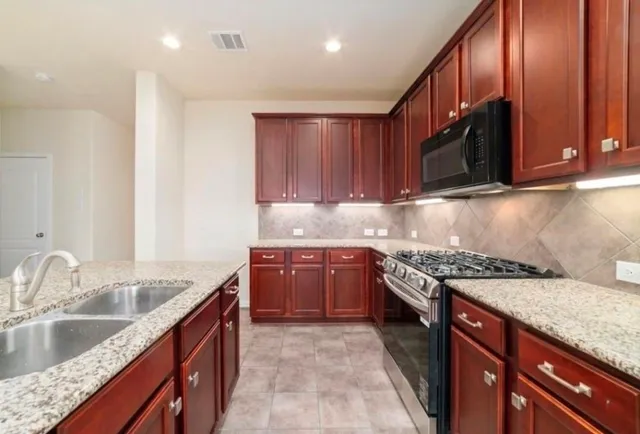 a kitchen with stainless steel appliances granite countertop a sink stove and cabinets