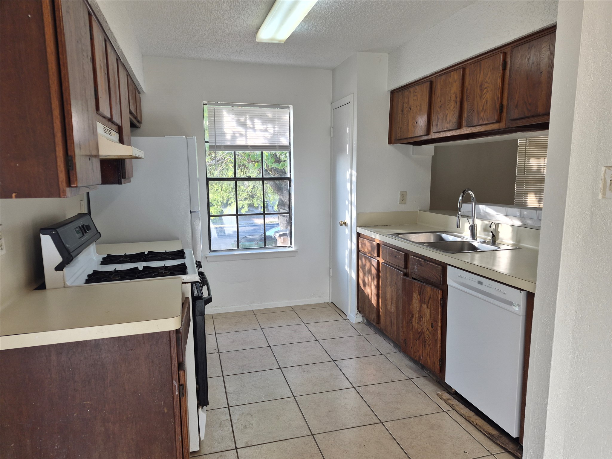 Classic wooden cabinets and tiled flooring define this practical kitchen layout.
