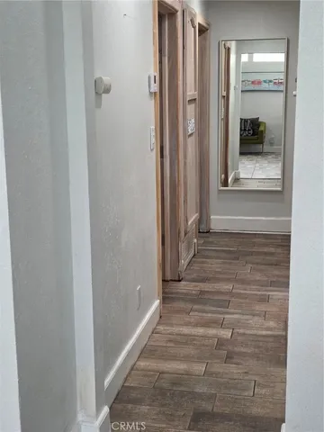 a view of a hallway with wooden floor and a bathroom