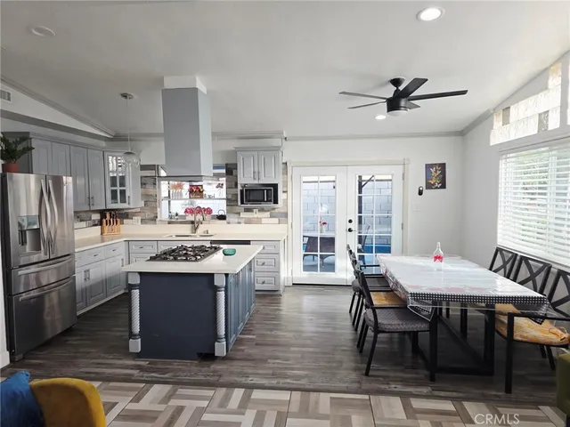 a kitchen with stainless steel appliances kitchen island granite countertop a table chairs and a refrigerator