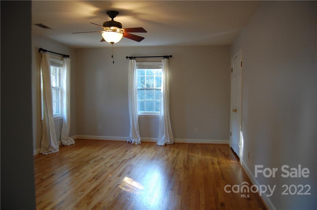 3101 Colony Road Charlotte, NC 28211 - Photo 24 of 26 an empty room with wooden floor chandelier fan and windows
