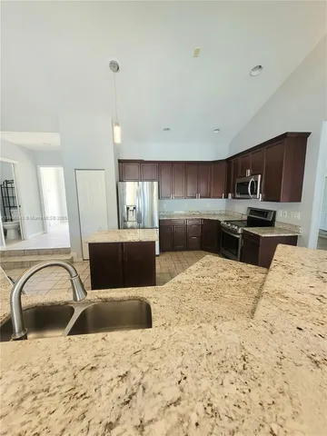 a large kitchen with stainless steel appliances kitchen island granite countertop a stove top oven a sink a dining table and chairs