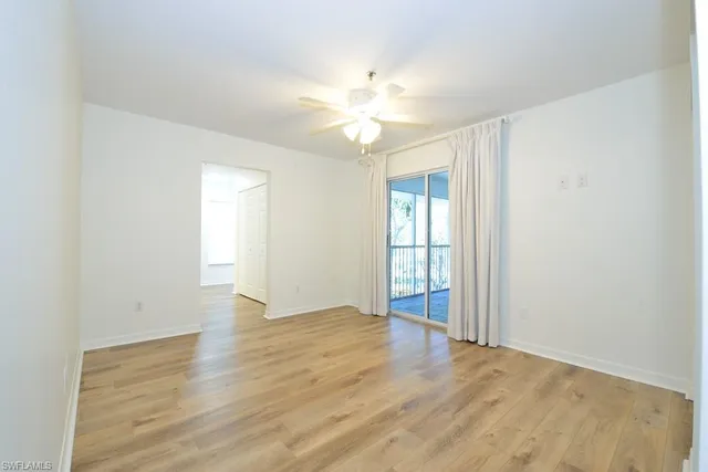 a view of an empty room with window and wooden floor