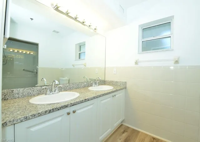 a bathroom with a granite countertop sink a mirror and a shower