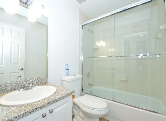 a bathroom with a granite countertop sink a toilet and shower
