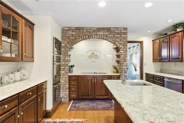a kitchen with kitchen island granite countertop a stove a sink and a wooden cabinets