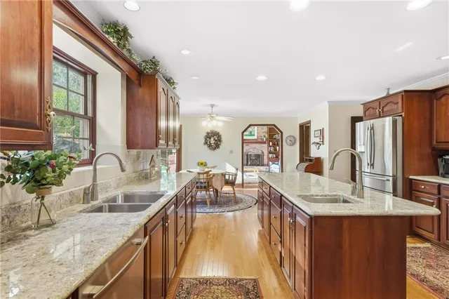 a large kitchen with granite countertop a large counter top a sink stainless steel appliances and cabinets