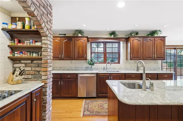 a kitchen with stainless steel appliances granite countertop a sink dishwasher and cabinets with wooden floor