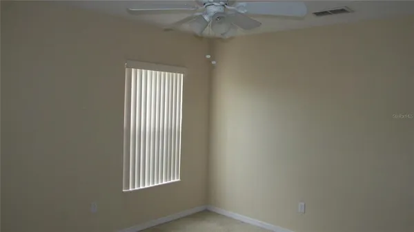 an empty room with a window and a chandelier fan