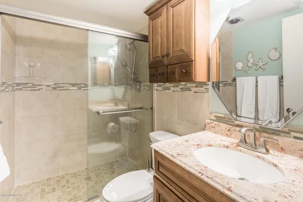 a bathroom with a granite countertop sink toilet and shower