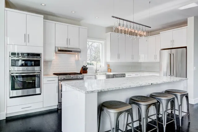 a kitchen with granite countertop white cabinets and stainless steel appliances