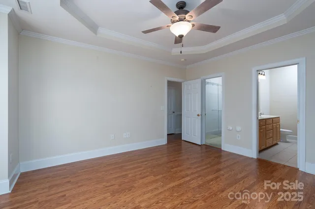 an empty room with wooden floor and ceiling fan