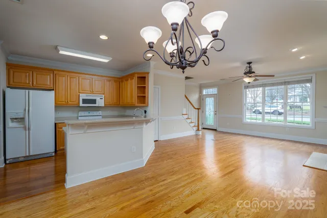 a kitchen with stainless steel appliances granite countertop a stove top oven a refrigerator a sink with wooden floors and couches