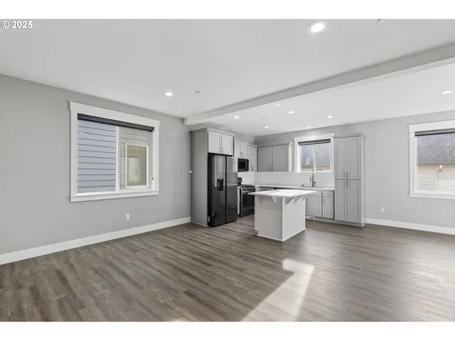 a kitchen with a refrigerator and wooden floor