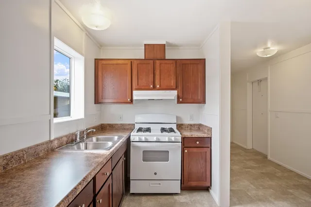 a kitchen with stainless steel appliances granite countertop a sink stove refrigerator and cabinets