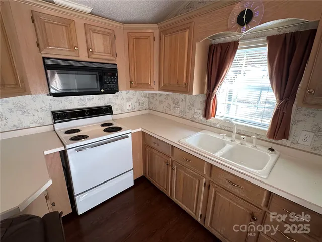 a kitchen with granite countertop a sink a microwave a stove and refrigerator