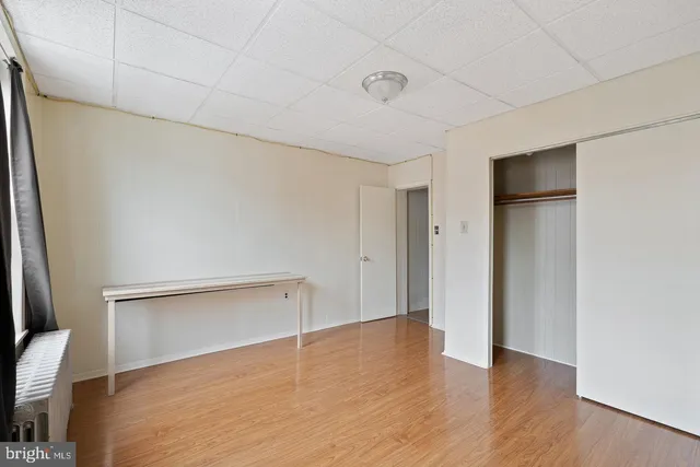 a view of an empty room with wooden floor and closet