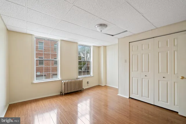 an empty room with wooden floor and windows