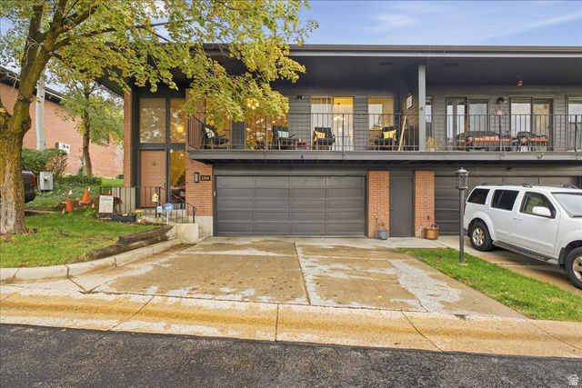 1334 Ridgewood Lane Bountiful, UT 84010 - Photo 1 of 38 Contemporary exterior with a brick and gray facade, featuring a private balcony with metal railings, an integrated garage, and a concrete driveway