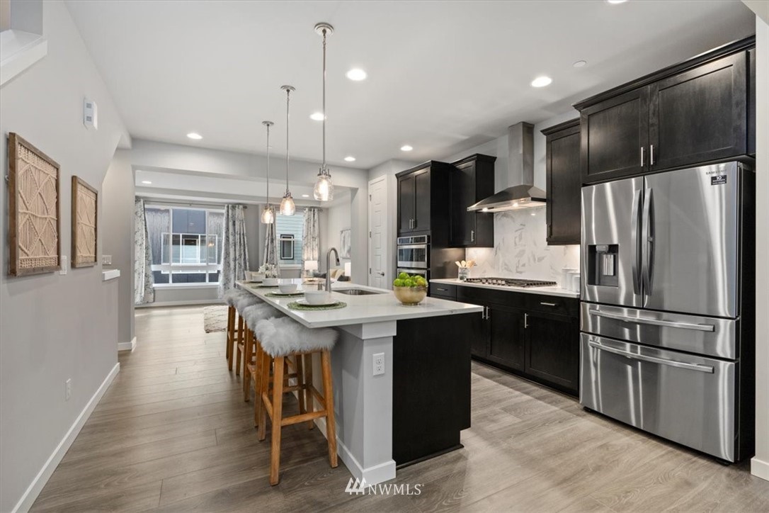 521 238th Place Southeast, Unit B Bothell, WA 98021 - Photo 8 of 21 a kitchen with kitchen island stainless steel appliances a sink a stove a table and chairs
