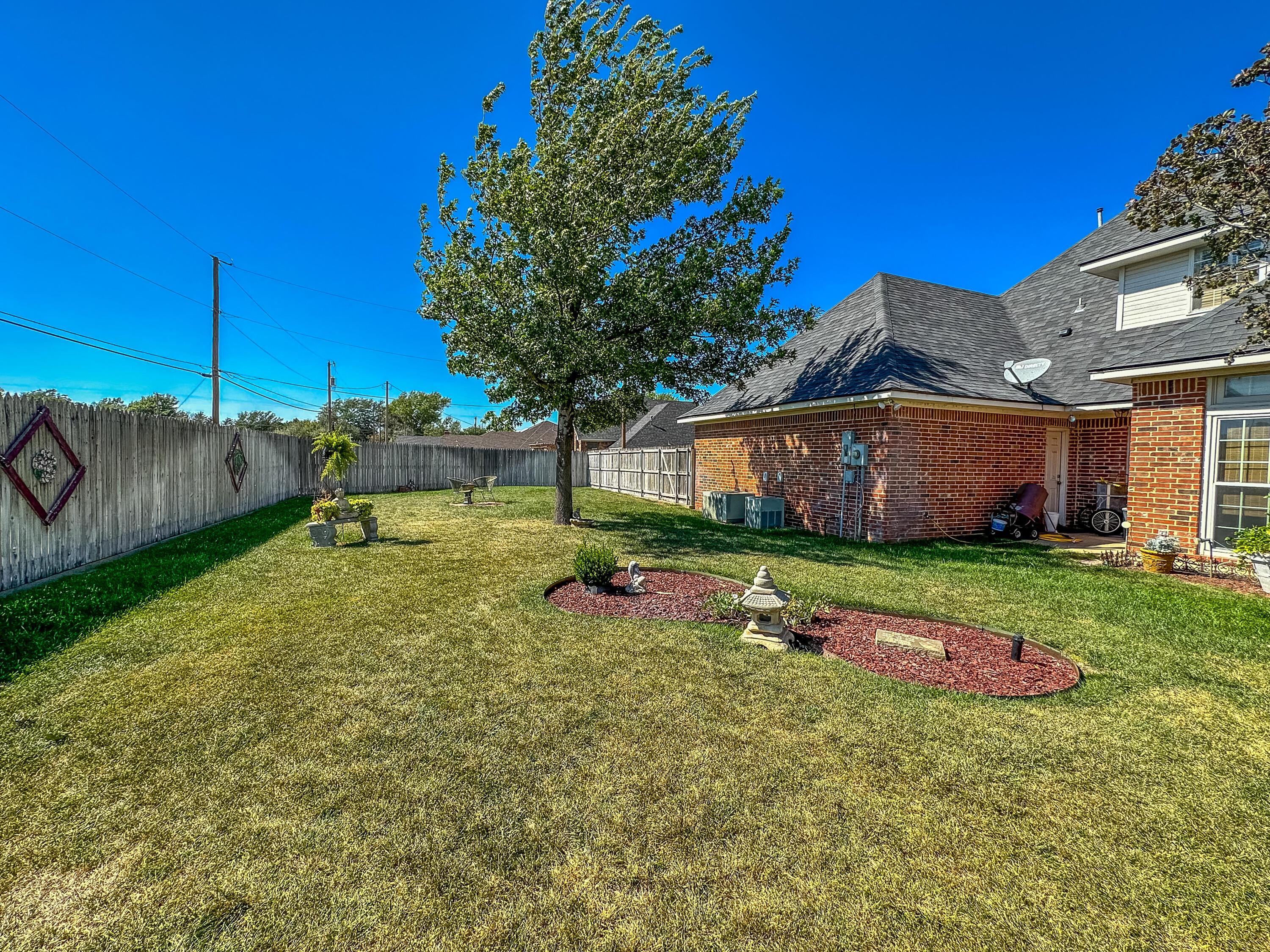 105 St James Street Borger, TX 79007 - Photo 34 of 36 a backyard of a house with table and chairs plants and large tree