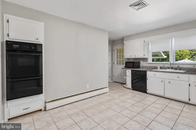 a kitchen with granite countertop white cabinets and refrigerator