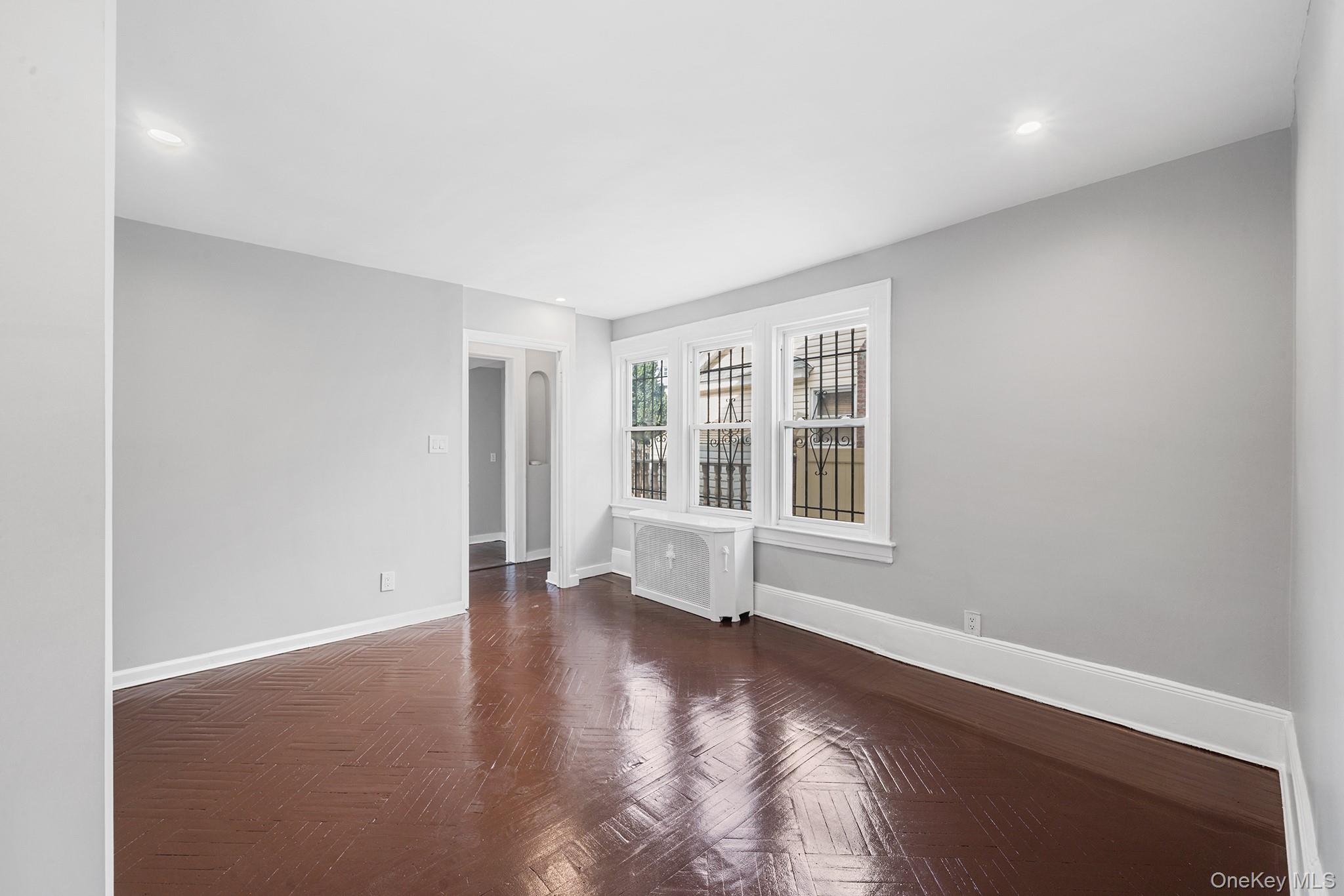 150-44 87th Road Queens, NY 11432 - Photo 11 of 35 an empty room with wooden floor and windows