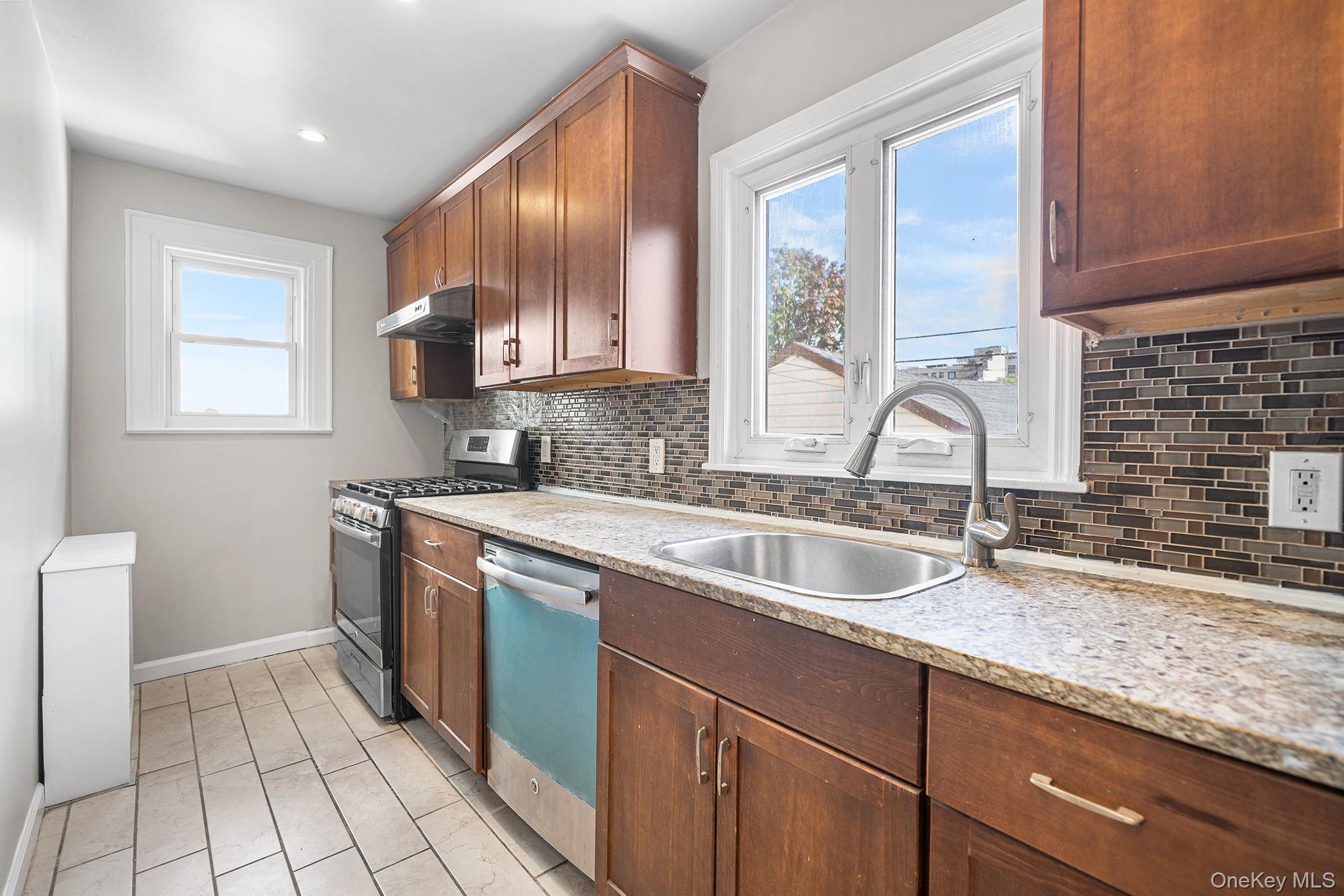 150-44 87th Road Queens, NY 11432 - Photo 14 of 35 a kitchen with a sink stove top oven and cabinets