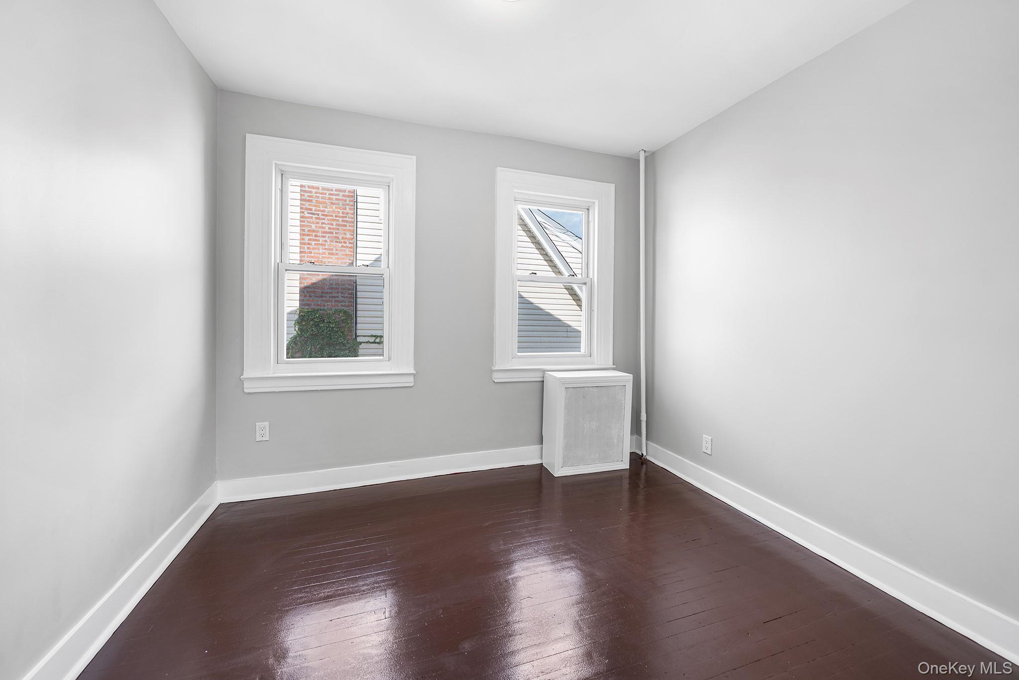 150-44 87th Road Queens, NY 11432 - Photo 18 of 35 an empty room with wooden floor and windows
