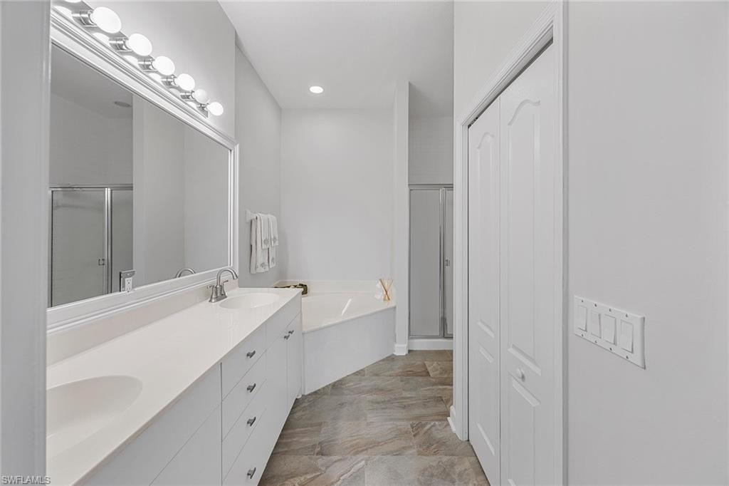 2432 Ravenna Boulevard, Unit 201 Naples, FL 34109 - Photo 20 of 50 a spacious bathroom with a double vanity sink and a mirror
