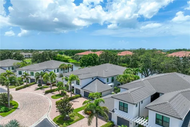 a view of a house with a yard plants and large tree