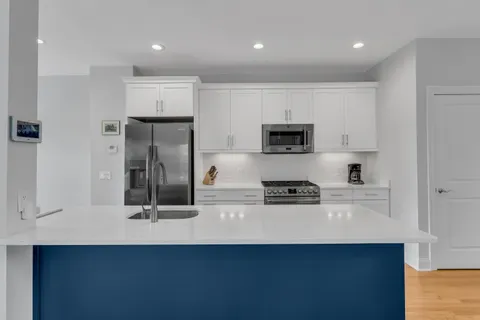 a kitchen with kitchen island a sink appliances and a counter top space