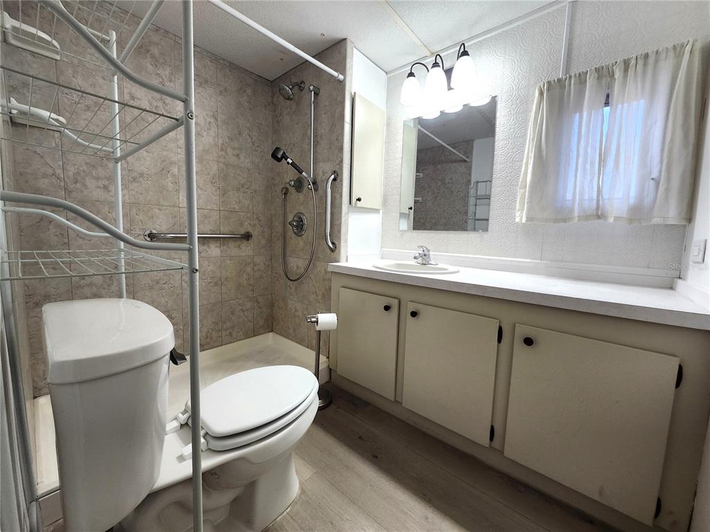 10129 East Bass Circle Inverness, FL 34450 - Photo 14 of 34 a bathroom with a toilet a sink a mirror a vanity and shower