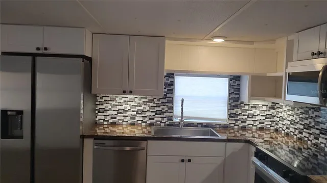 a kitchen with stainless steel appliances granite countertop a sink and a refrigerator