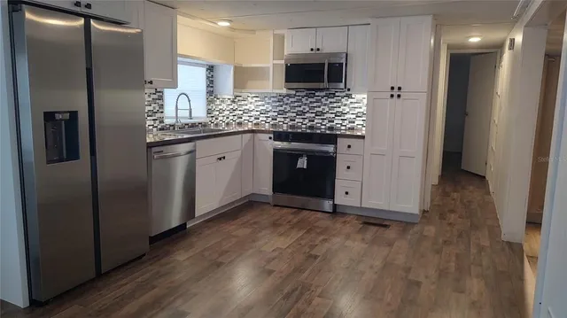 a kitchen with stainless steel appliances kitchen island granite countertop a refrigerator and a sink