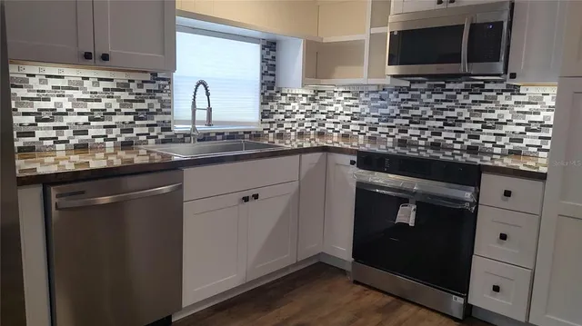 a kitchen with granite countertop white cabinets and stainless steel appliances