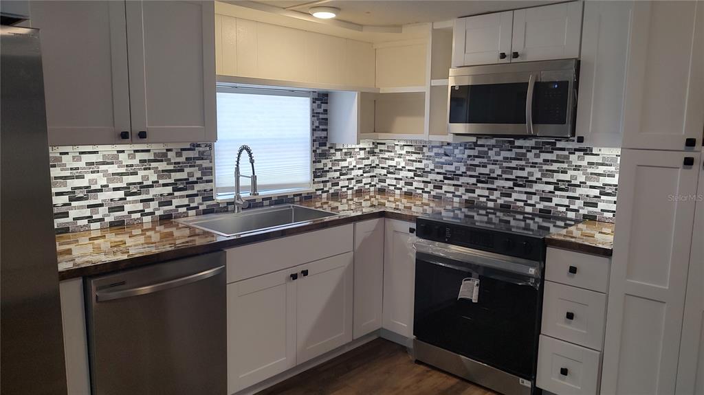 10129 East Bass Circle Inverness, FL 34450 - Photo 33 of 34 a kitchen with granite countertop white cabinets and stainless steel appliances