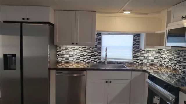 a kitchen with kitchen island a counter top space cabinets and stainless steel appliances