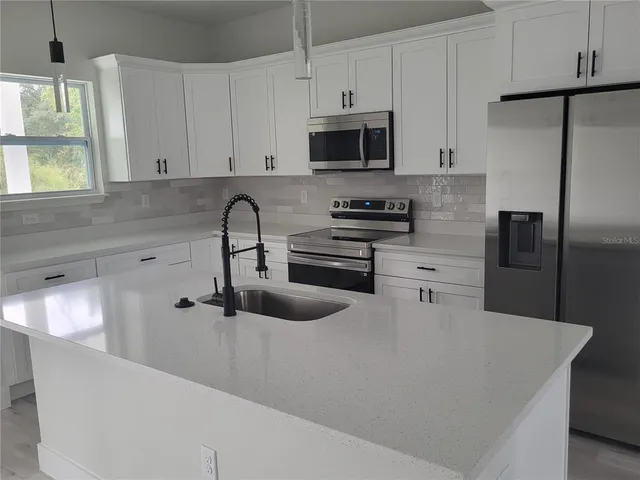 a kitchen with stainless steel appliances a sink a stove a refrigerator and cabinets