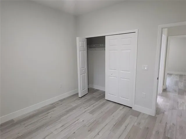 an empty room with wooden floor & closet area