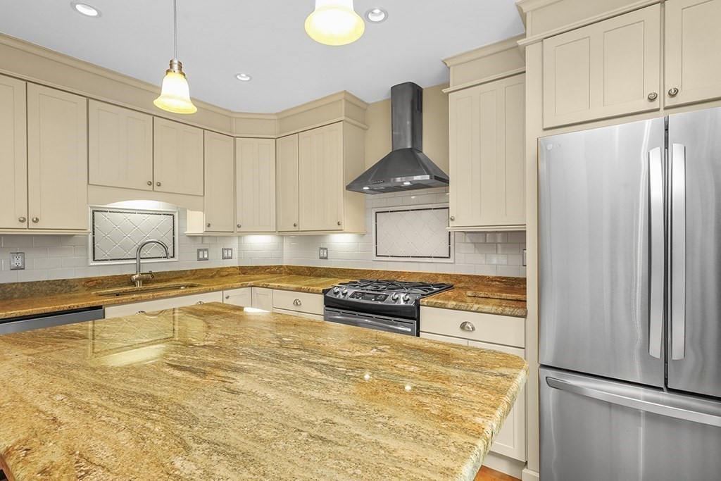 339 Winthrop Street Winthrop, MA 02152 - Photo 9 of 42 a kitchen with kitchen island granite countertop a refrigerator a stove and white cabinets with wooden floor