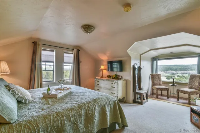 a spacious bedroom with a bed a table and large windows