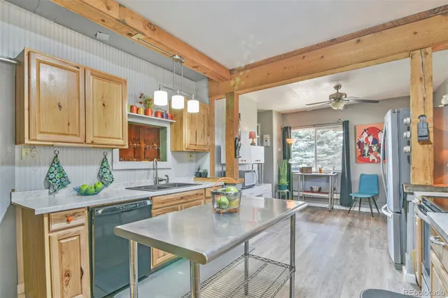 a kitchen with stainless steel appliances granite countertop a sink a stove a dining table and chairs with wooden floor